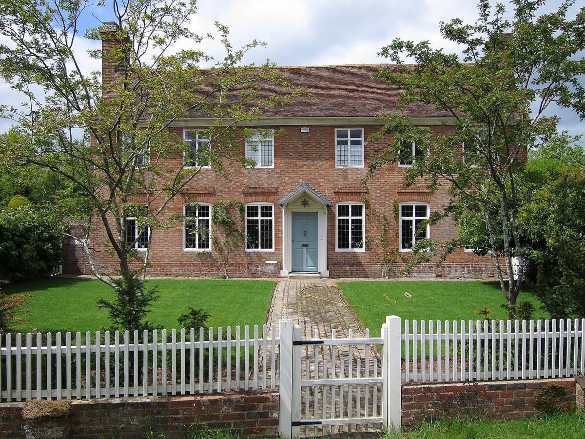 A Georgian red-brick detached house behind a white picket fence in Biddenden, Kent