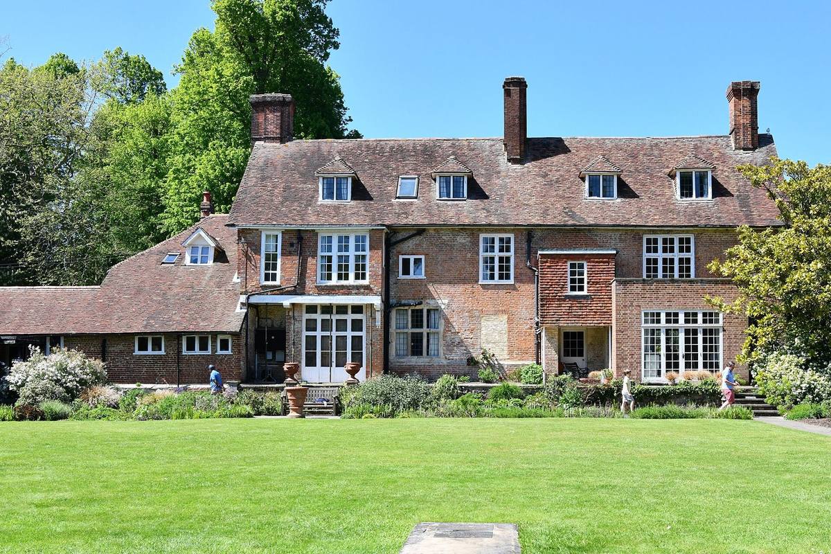 A seventeenth-century red-brick manor house with tall chimneys and a large lawn
