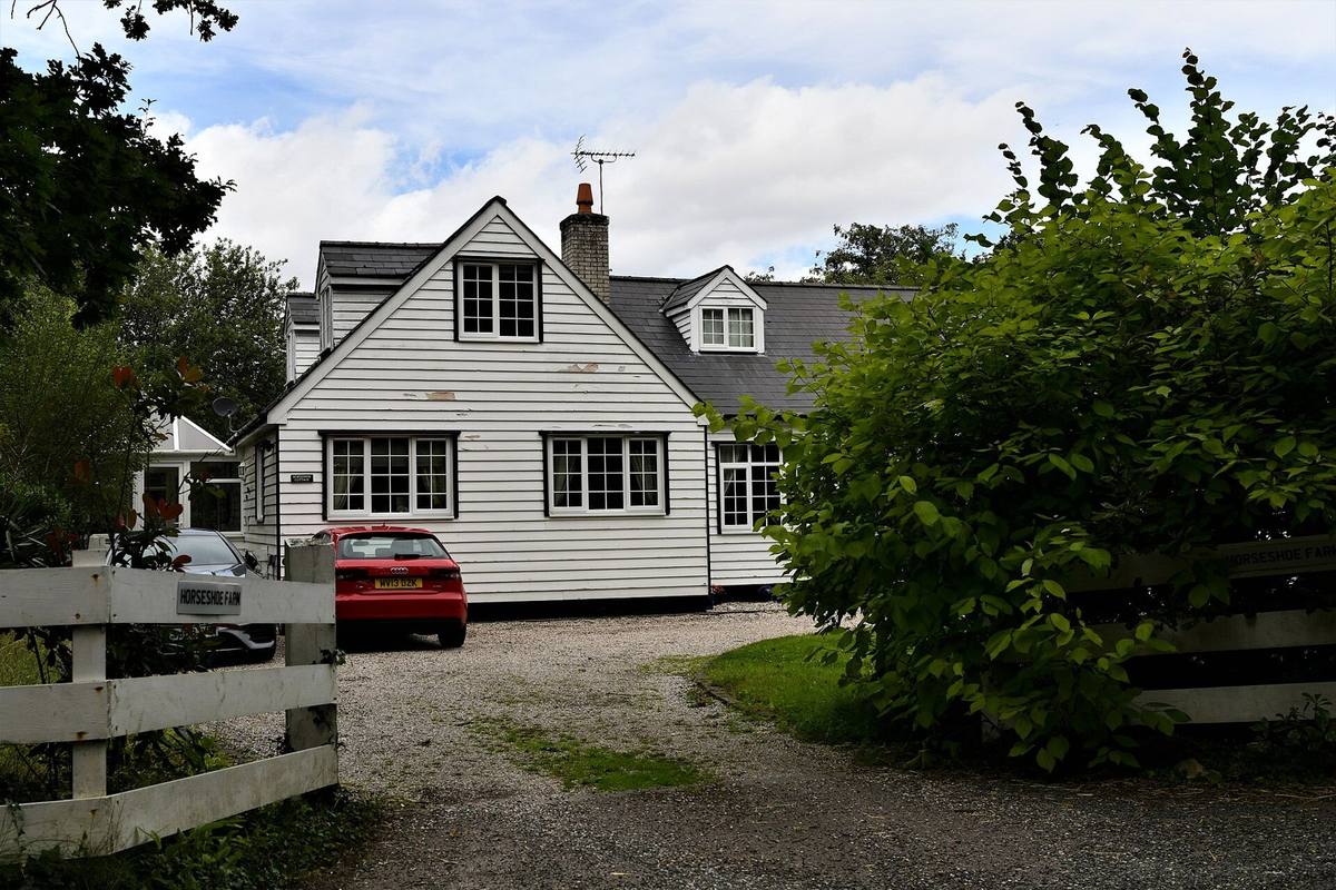 A large white-rendered detached farmhouse with a gravel drive in Orlestone, south of Ashford