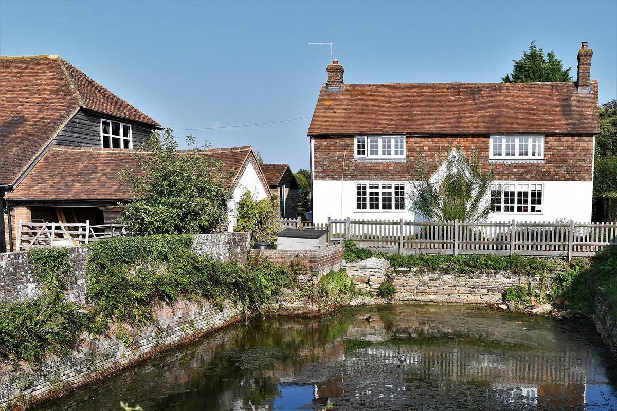 A red-brick Kent farmhouse beside a pond and garden near Tenterden